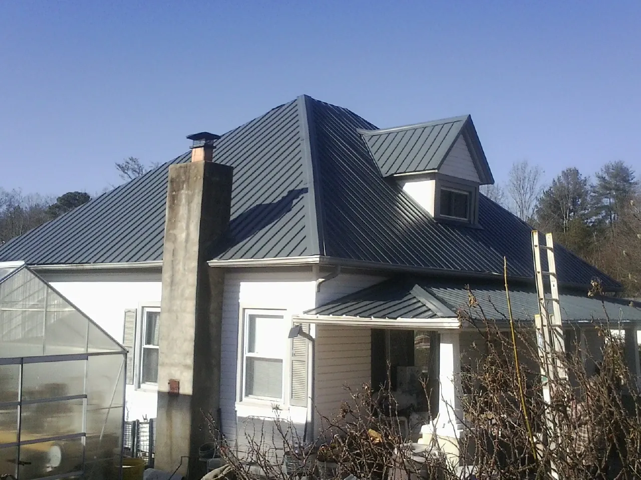 Dark blue standing seam metal roof on a white farmhouse with dormer — Slate & Tile Roof Repair by Roofing Brothers in Walling