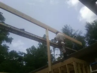 Carpenter setting a ridge beam over a new addition frame — Ice Dam Removal by Roofing Brothers in Walling