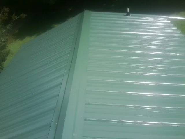 New green metal panels meeting at the ridge of a roof — Flat Roof Repair work by our crew in Walling